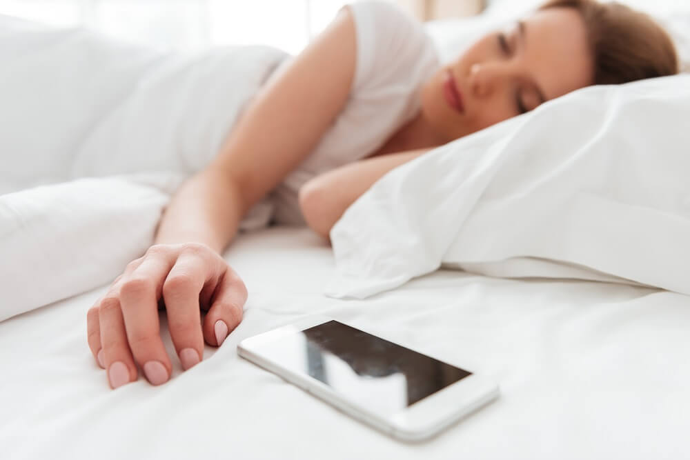 sleeping woman with phone on bed