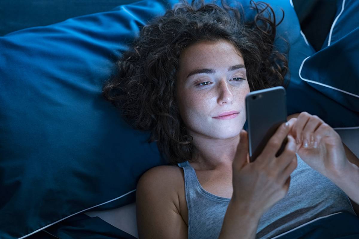 Woman using phone at night now knowing how it affects sleep