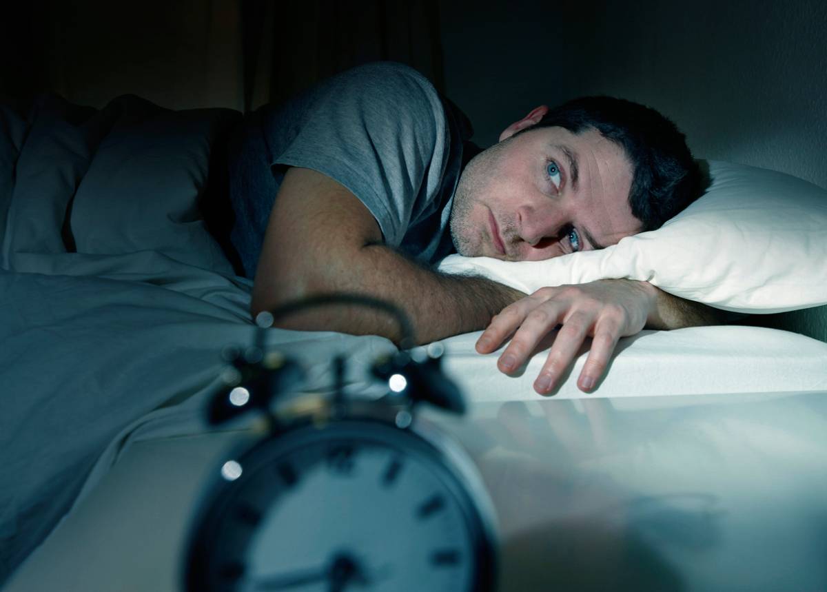 Man lying in bed with hormones that interfere with sleep.