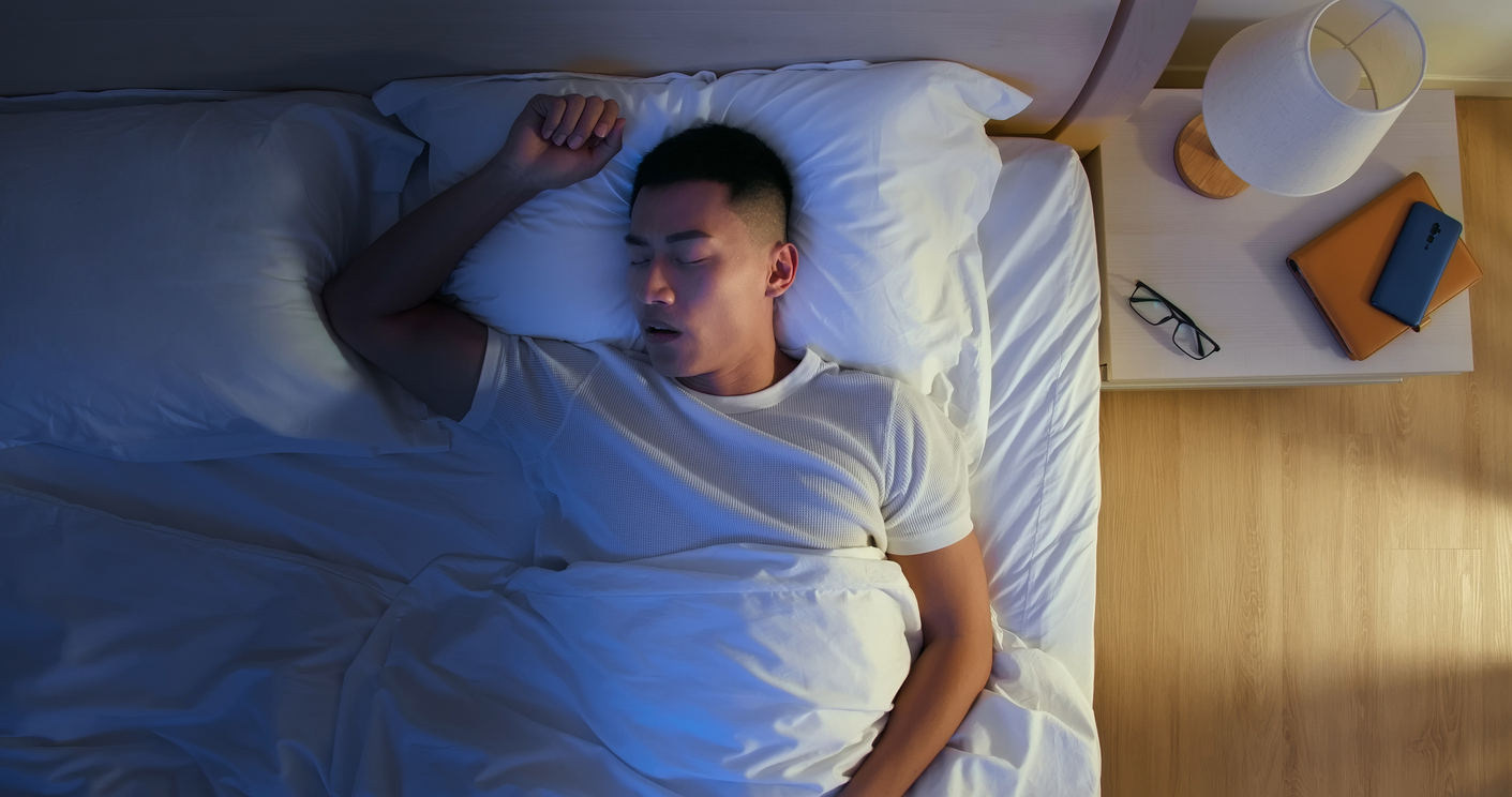 The image shows a man snoring at night to explain the age snoring will often begin.
