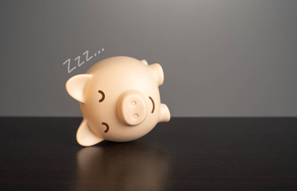 sleepy piggy bank on its side representing trying to make up sleep debt concept