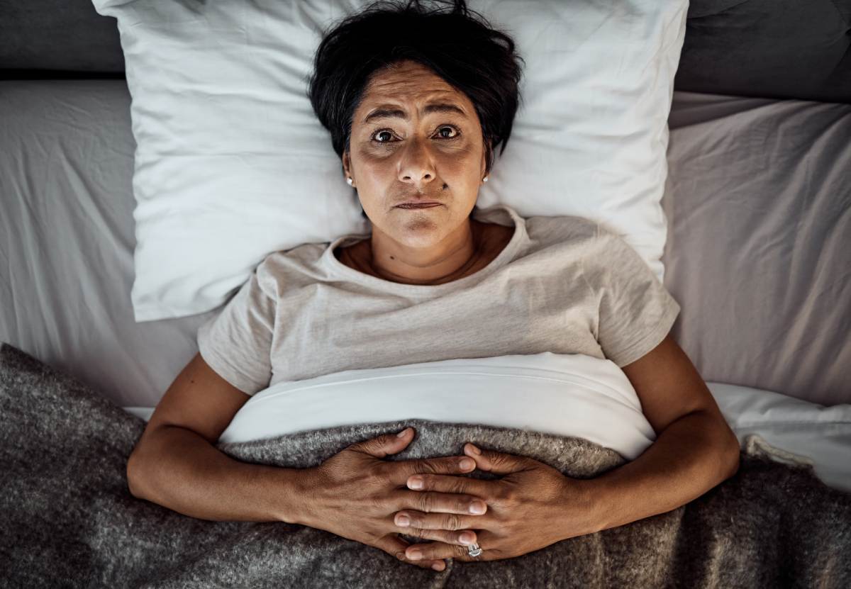 Woman lying awake in bed with insomnia, showing difficulty sleeping and restlessness at night.