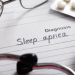 Paper with "Sleep apnea" diagnosis written on it, with stethoscope and pills nearby.