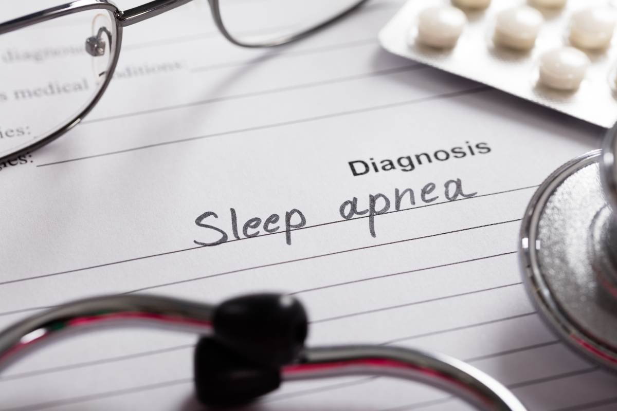 Paper with "Sleep apnea" diagnosis written on it, with stethoscope and pills nearby.