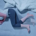 Woman With RLS - Restless Legs Syndrome. Sleeping In Bed