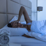 Woman with insomnia lying in bed with open eyes.